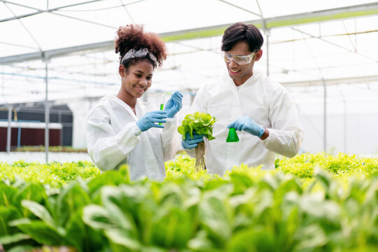 Two people are in a greenhouse, one of them is holding a bell