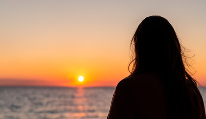 a woman watching a sunset on a torpical beach generated with artificial intelligence