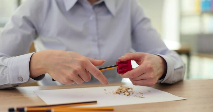 Woman office worker rotates pencil in blade of sharpener