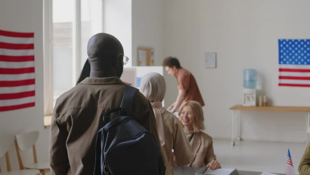 Group of multi-ethnic people walking into polling place, receiving ballots and going to voting booths during Election day