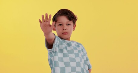 Young boy, face and stop in tshirt on studio background for warning, protest and wrong action. Child, portrait and hand up sign with upset, caution and casual for communication, opinion and decision