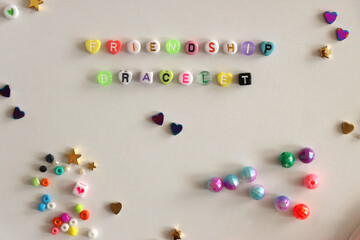 Making friendship bracelets with letter beads. Jewelry making supplies on the table. Flat lay.