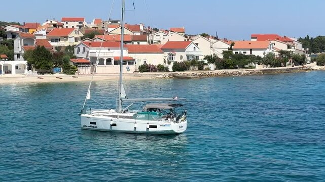 A white sailboat sails on the blue sea. Boat with a sail on the birch water of the Adriatic sea. Sailing holidays off the Croatian coast, Preko island, June 27, 2024