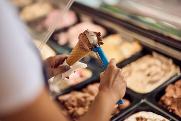 Close-up of a chocolate ice cream in a cone, putting with a scooper.