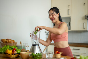 A woman is making a smoothie in a kitchen