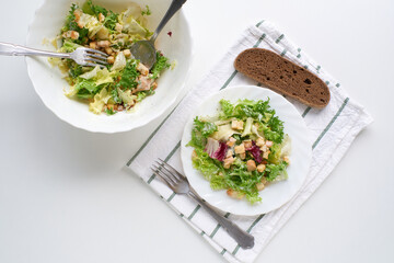 Fresh Caesar salad with croutons and bread on white surface