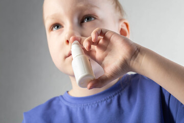 A girl sprays a spray against runny nose and nasal congestion into her sinuses. Treatment of sinusitis and sinusitis, antimicrobial spray, close-up