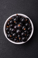 Ripe blackcurrant berries in droplets of water in a ceramic bowl