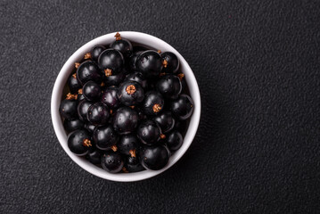 Ripe blackcurrant berries in droplets of water in a ceramic bowl