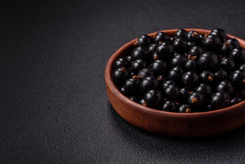Ripe blackcurrant berries in droplets of water in a ceramic bowl