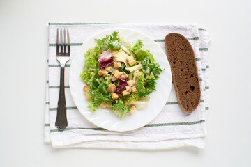 Fresh Caesar salad with croutons and bread on white surface