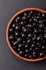 Ripe blackcurrant berries in droplets of water in a ceramic bowl