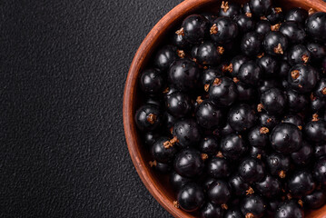 Ripe blackcurrant berries in droplets of water in a ceramic bowl