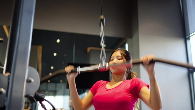 Young asian woman fitness exercises at gym lat pulldown machine, Making an effort and training hard for fit body, Healthcare, Firm exercise, healthy fit and Sport concept, Female training