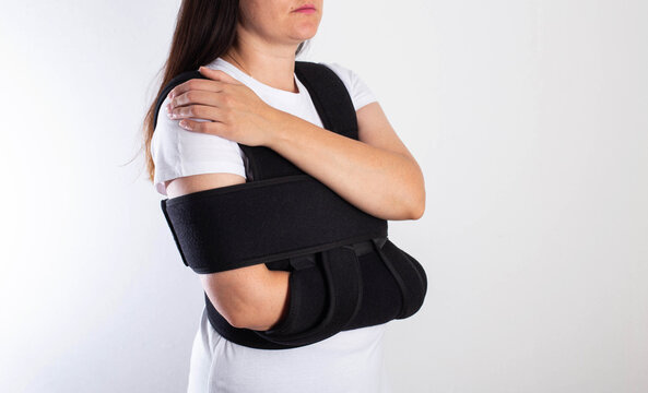 A girl in a black medical brace on the shoulder joint for rehabilitation after a fracture of the humerus and dislocation. Post-traumatic immobilization of the shoulder joint 