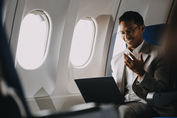 Asian businessman enjoying enjoys a coffee comfortable flight while sitting in the airplane cabin, Passengers near the window.