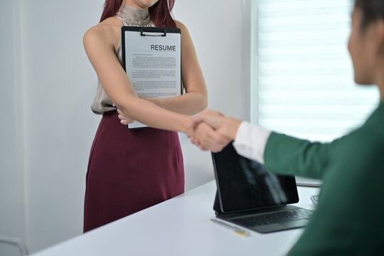 Professional Job Interview with Candidate Handshake and Resume in Modern Office Setting
