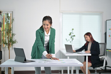 Professional Businesswomen Collaborating in Modern Office with Digital Devices and Charts