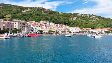 Naklejka premium Picturesque town on a croatian island with tourists relaxing by the sea on a sunny summer day