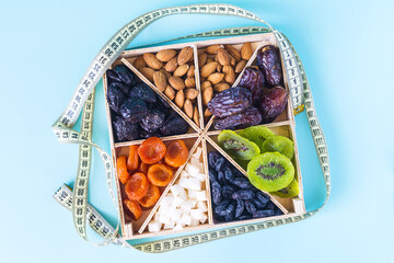 Assorted various dried fruits and nuts on a wooden stand and a measuring tape in close-up