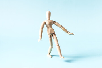 The concept of a walking person who takes a step forward. A wooden doll takes a step forward on a light background.