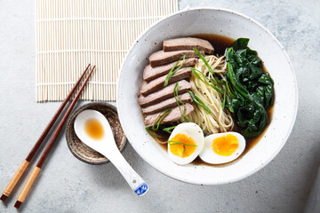 A bowl of ramen with slices of beef, soft-boiled egg halves, and green vegetables. The meal is garnished with green onions