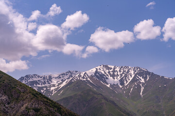 Fototapeta premium The sky is blue with clouds and the mountains are covered in snow