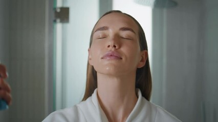Woman spraying face water in bathroom closeup. Pretty lady using moisturizer