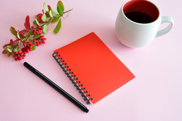 a red notebook with a pen on it next to a cup of coffee   