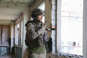 Military mission. Soldier in uniform with radio transmitter inside abandoned building