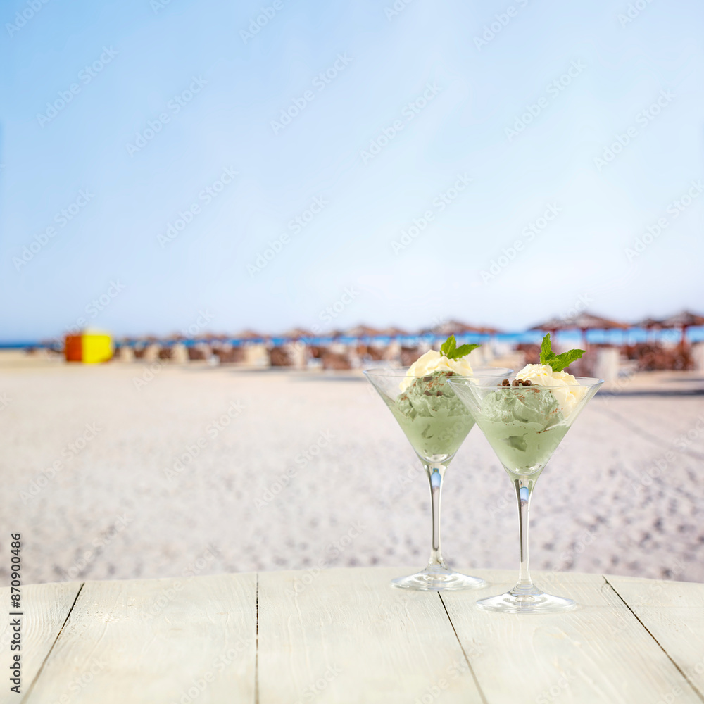 Wall mural Two glasses with ice cream and mint leaves on a sandy shore of the sea. the concept of a summer vacation. Relaxation time. Copy space for advertising products