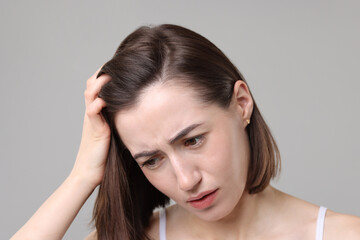 Naklejka premium Sad woman with hair loss problem on grey background