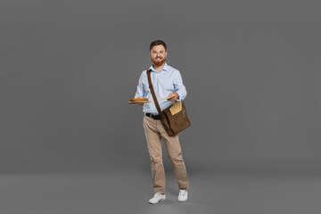 Postman with brown bag delivering letters on grey background