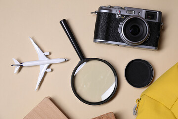 Travel blogger. Flat lay composition with vintage camera and magnifying glass on beige background
