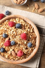 Tasty granola with fresh berries and nuts on wooden table, flat lay