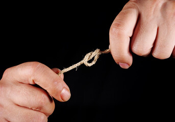 hands of person holding rope in dark
