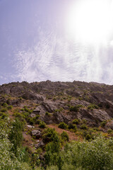 A mountain with a cloudy sky and a sun shining on it