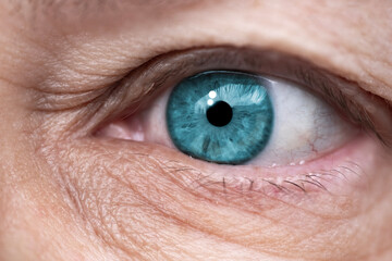 close-up mature female eye looking to side, concept of patient care, wrinkles around eyes, upper...