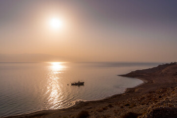 Fototapeta premium The alone fishing boat on the water of Dead Sea close to Israel coast (Ein Gedi) during the colorful sunset in the Middle East. 