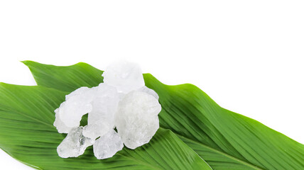 White crystal clear alum cube on green leaf isolated on white background.