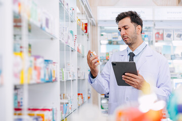 Pharmacy shop manager male staff looking medicine detail at drugstore, checking products...