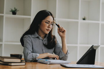 Portrait of Asian young female working on laptop and financial report at office.