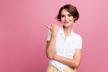 Photo of overjoyed woman with bob hairdo dressed white shirt directing look at promo empty space isolated on pink color background