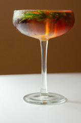 A glass of cocktail with a garnish of rosemary on top