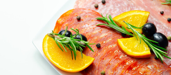 A plate of cold meat with a slice of orange on top