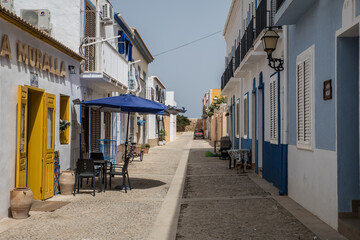 A Narrow Street in a Spanish Town With a Blue Umbrella and Yellow Door © evalco