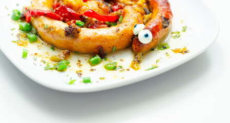 A plate of food with a sausage that has eyes on it