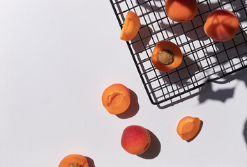 Organic ripe apricots under sun shadows on the white table top view