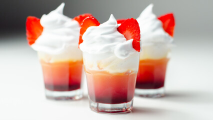 Three glasses of strawberry shot drink with whipped cream