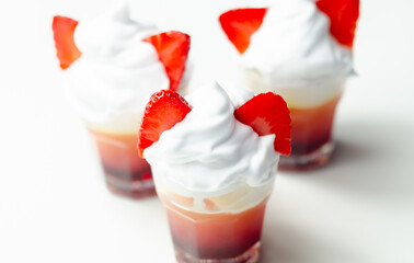 Three glasses of strawberry shot drink with whipped cream